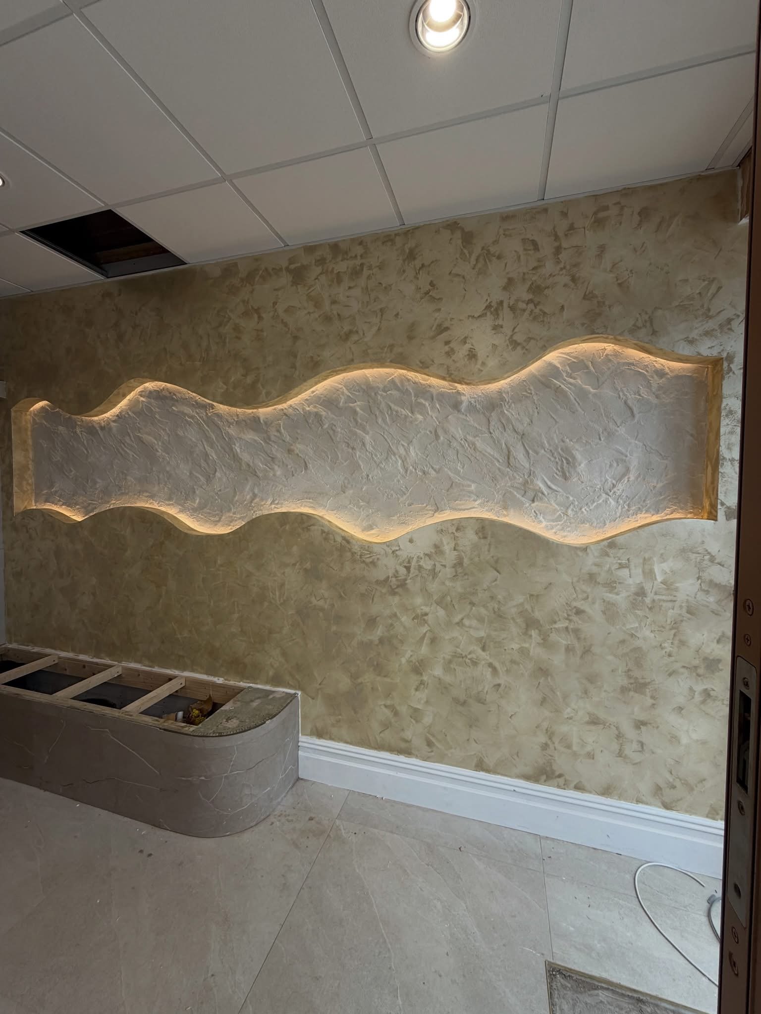 Pared de estuco veneciano con hornacina retroiluminada en un salón reformado en Sevilla